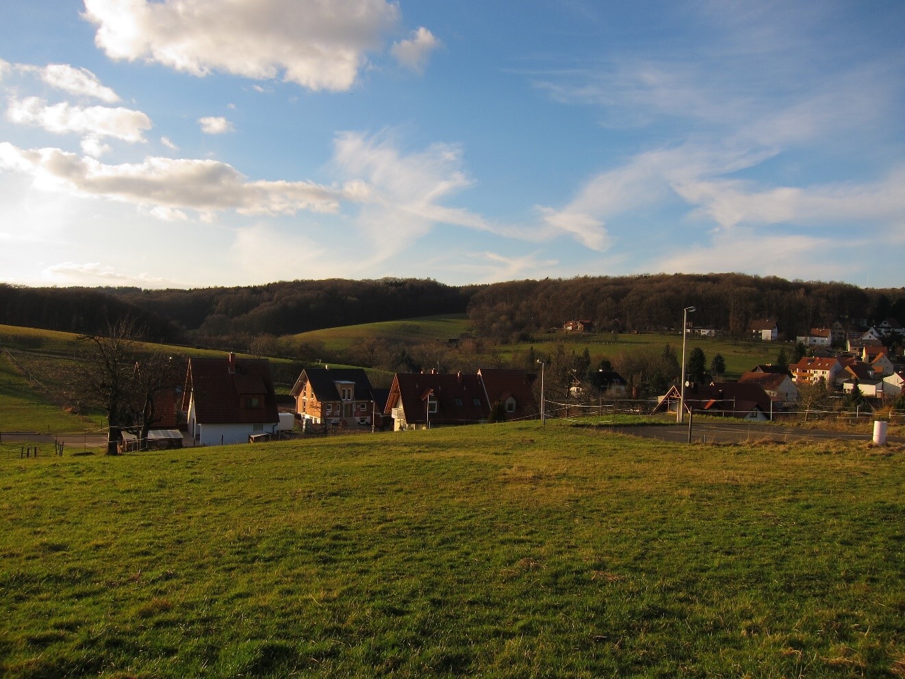 Rural landscape with houses on a hillside, green fields and blue sky