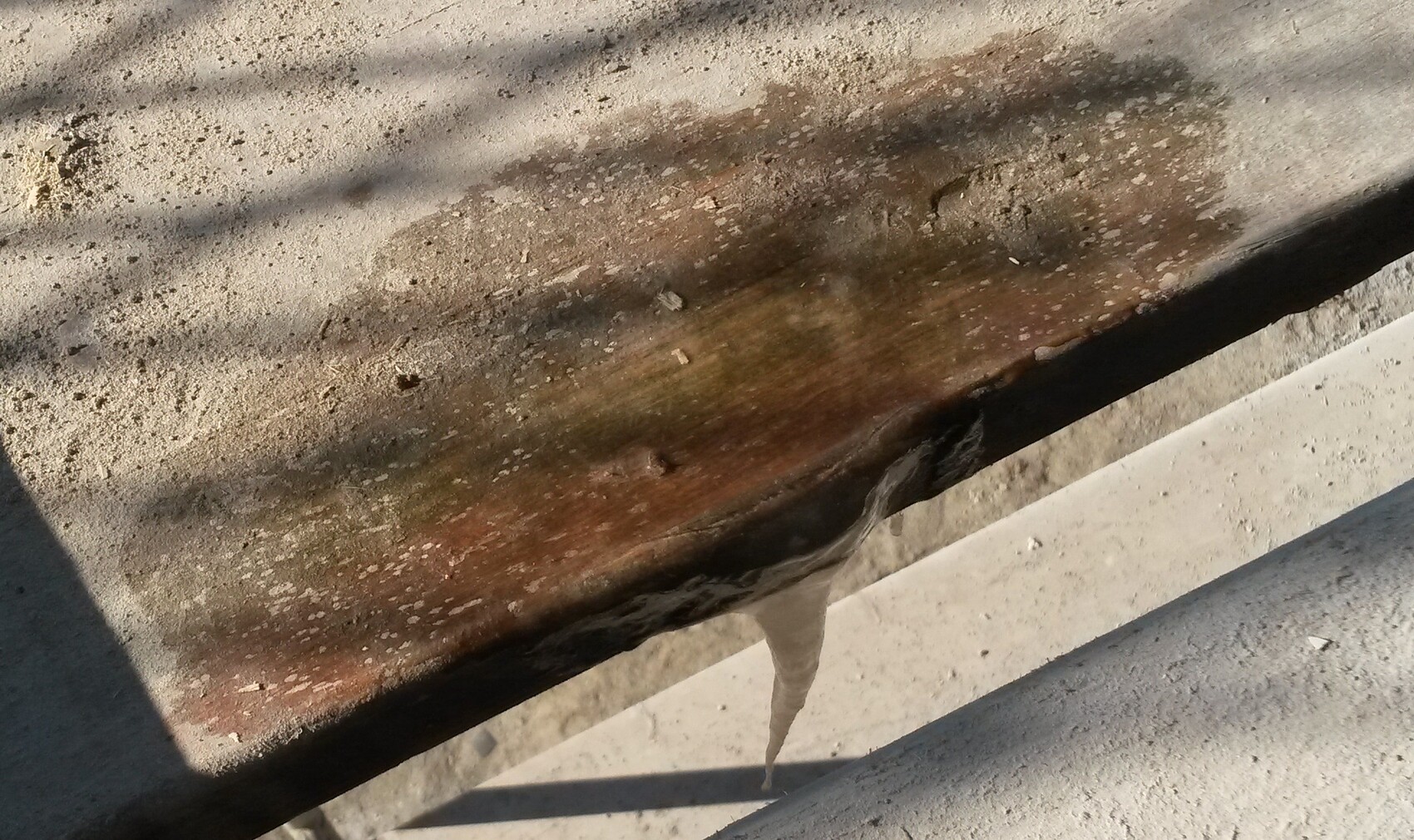 Close-up of a rusty beam on a building structure with dust and water droplets