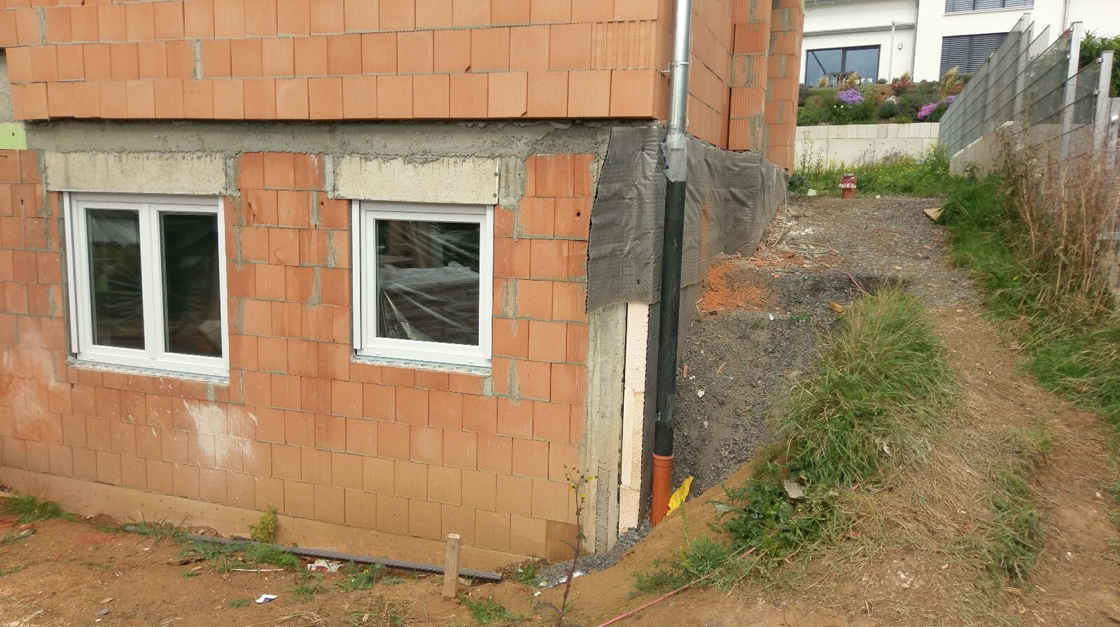 Exterior view of a shell construction house with brick wall and windows.