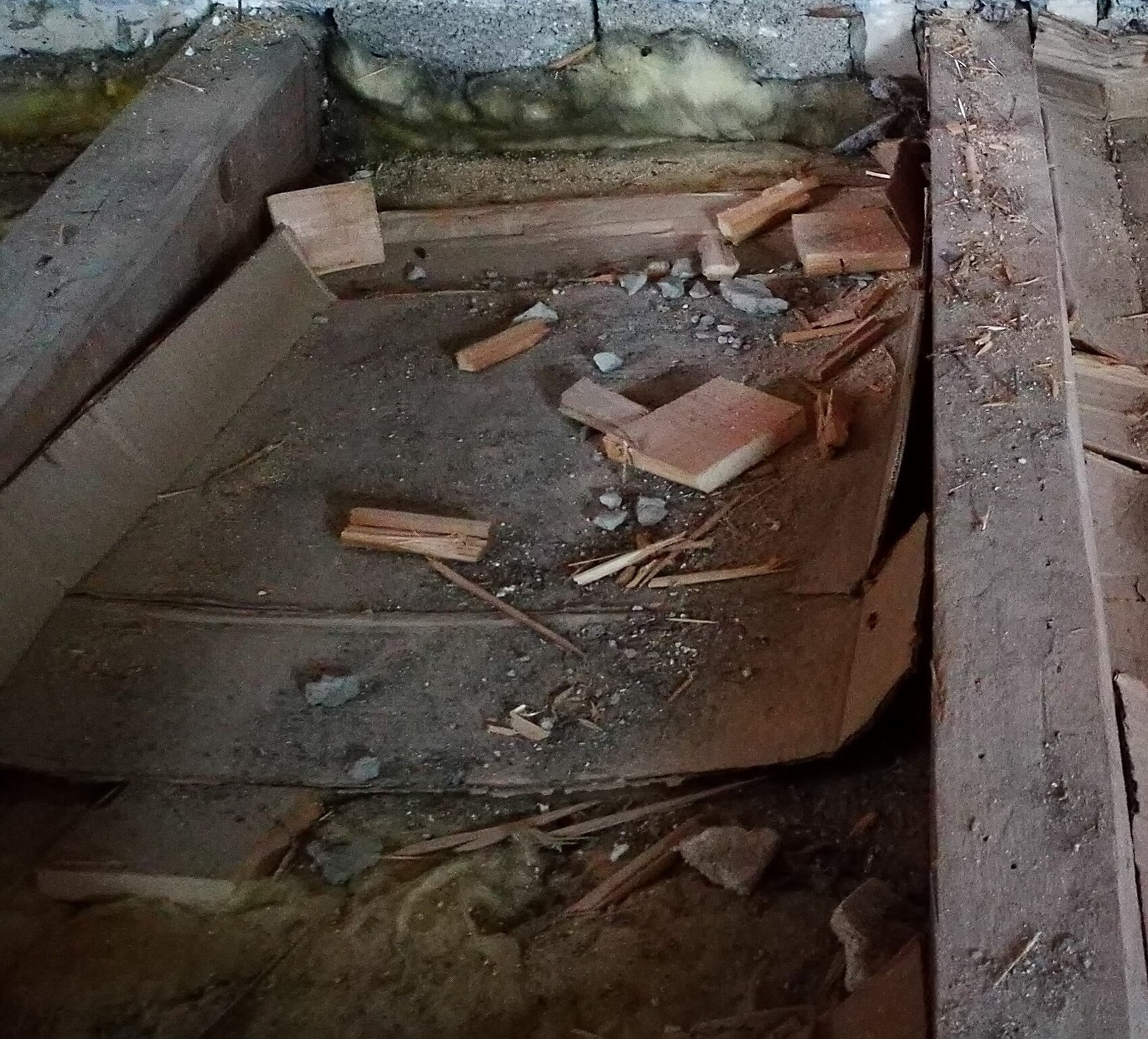 Holzbretter, Steine und Bauabfall liegen auf einem Kellerboden bei Rohbauarbeiten.