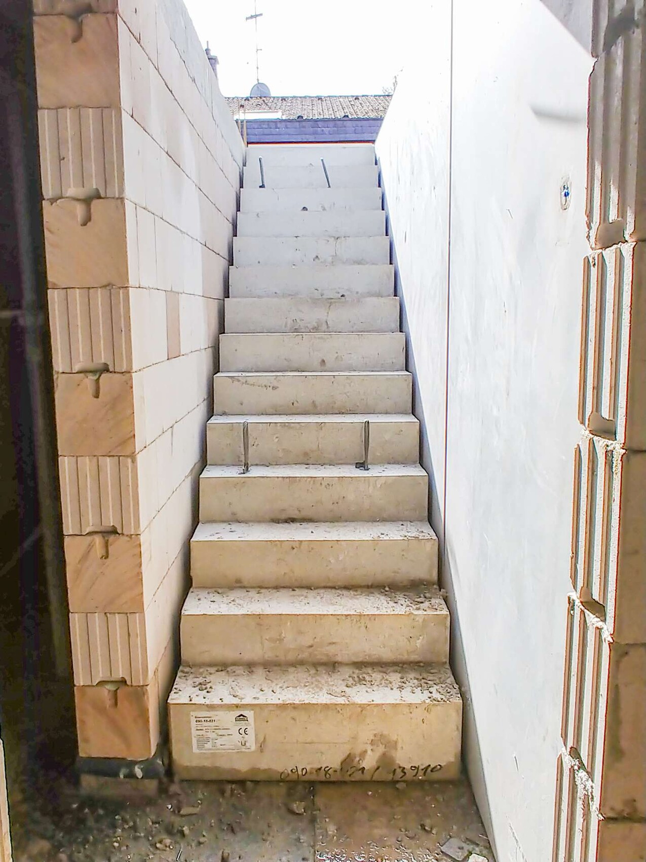 White concrete staircase between two walls outdoors, view looking up.