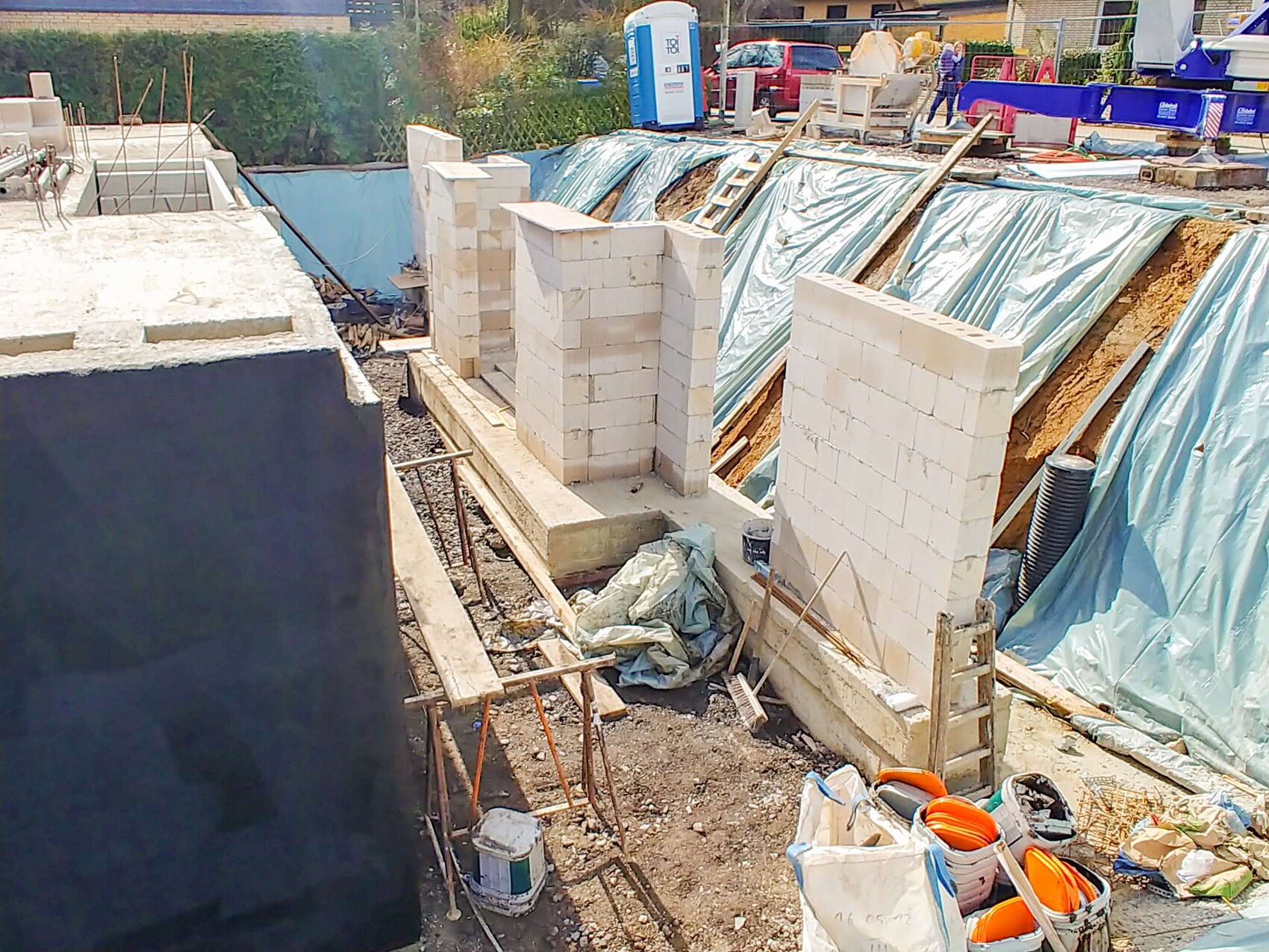 Construction site with white blocks as walls of a pit, construction tarps and tools visible.