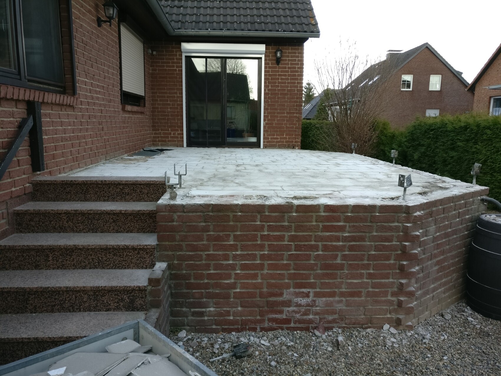 Terrace made of brick with steps and concrete floor behind the house