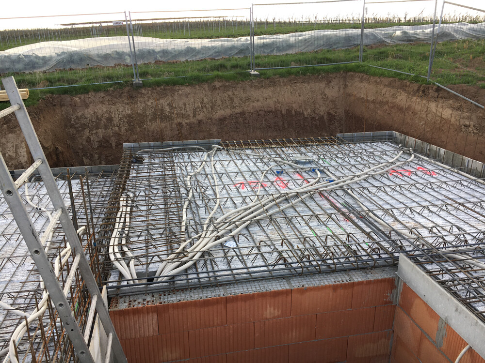 Foundation with reinforcement steel mesh and cable bundles; construction fence surrounding the site.