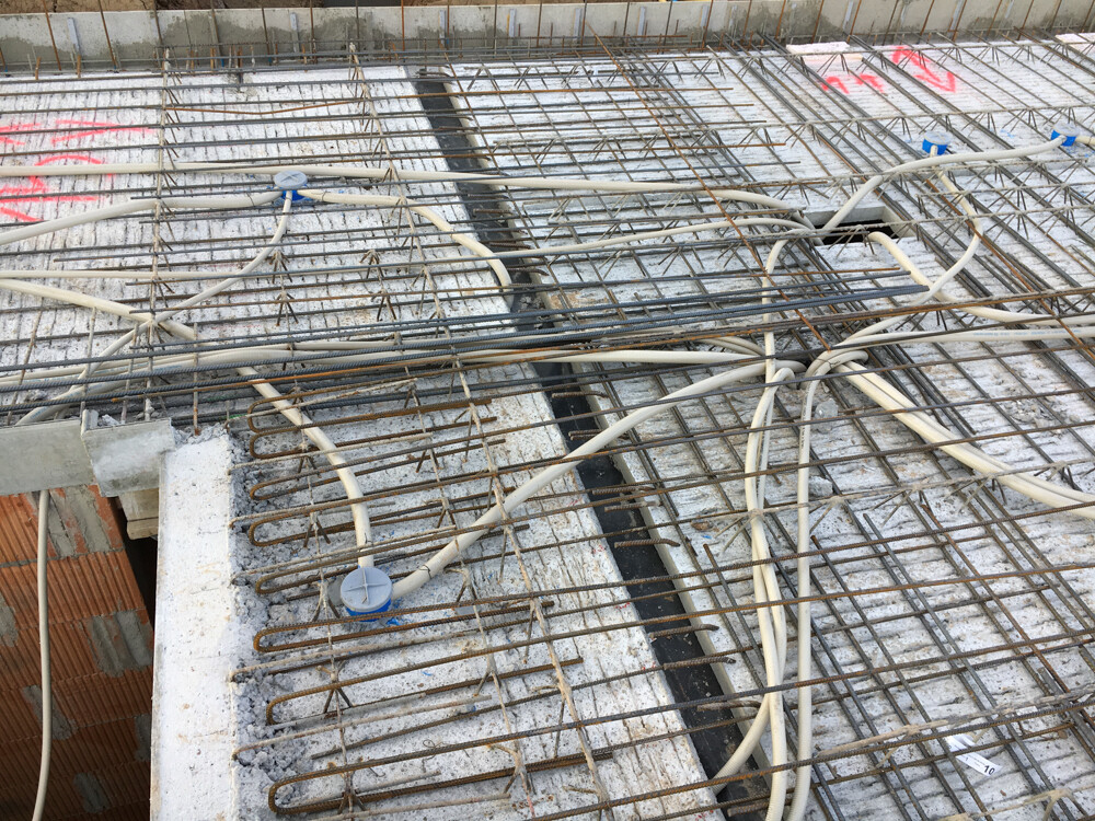 Reinforcement steel mesh and multiple cables on a concrete surface at a construction site.