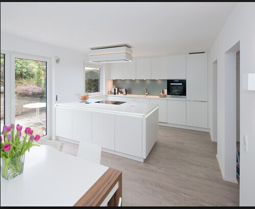 Modern white kitchen with island, dining table, and large windows