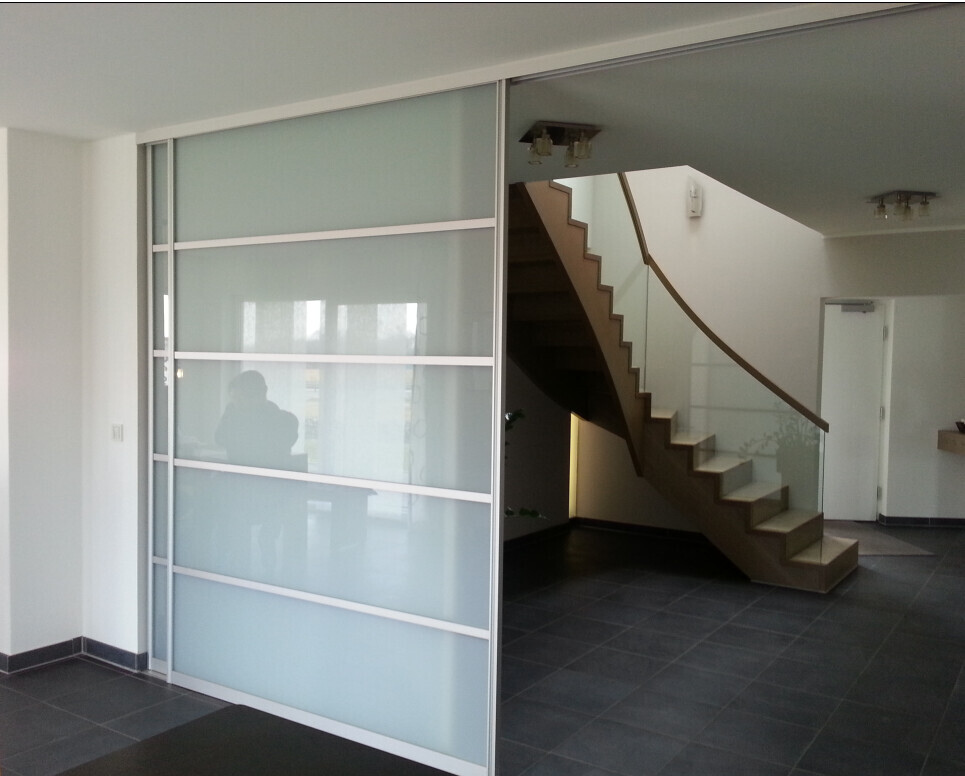 Modern interior view with glass partition on the left and curved staircase on the right.
