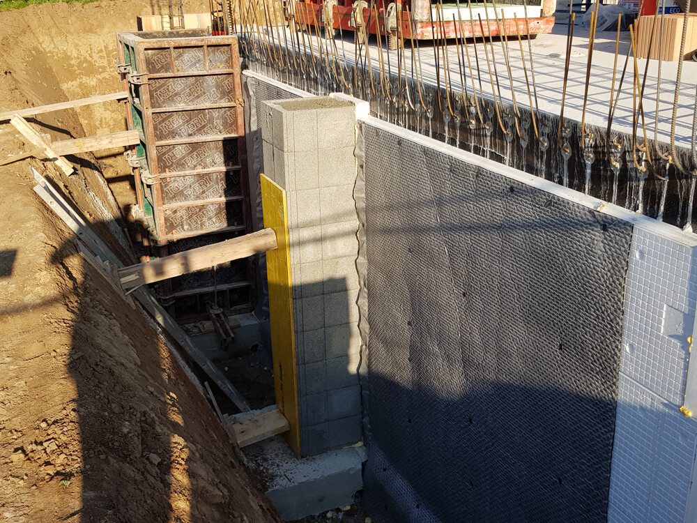 Construction site: foundation wall made of concrete blocks, reinforcement and earthworks.
