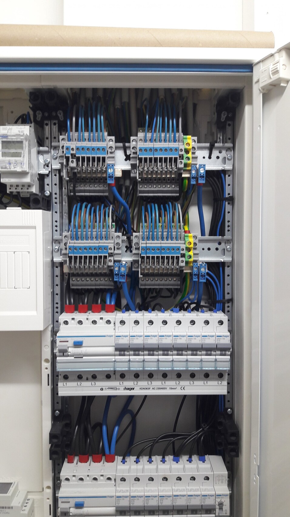 Electrical panel with many blue cables, terminal blocks, and fuses