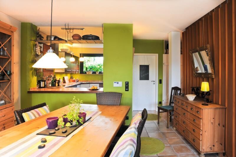 Bright kitchen and dining area with green wall, wooden table, and sideboard