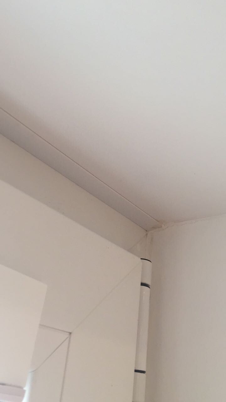 Weißer Türrahmen im Eckbereich einer weißen Wand, Türangel sichtbar