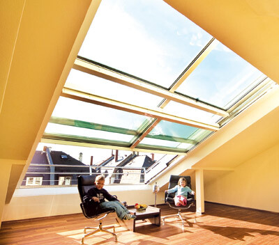 Bright attic living room with roof windows, wooden floor, and two children sitting on chairs