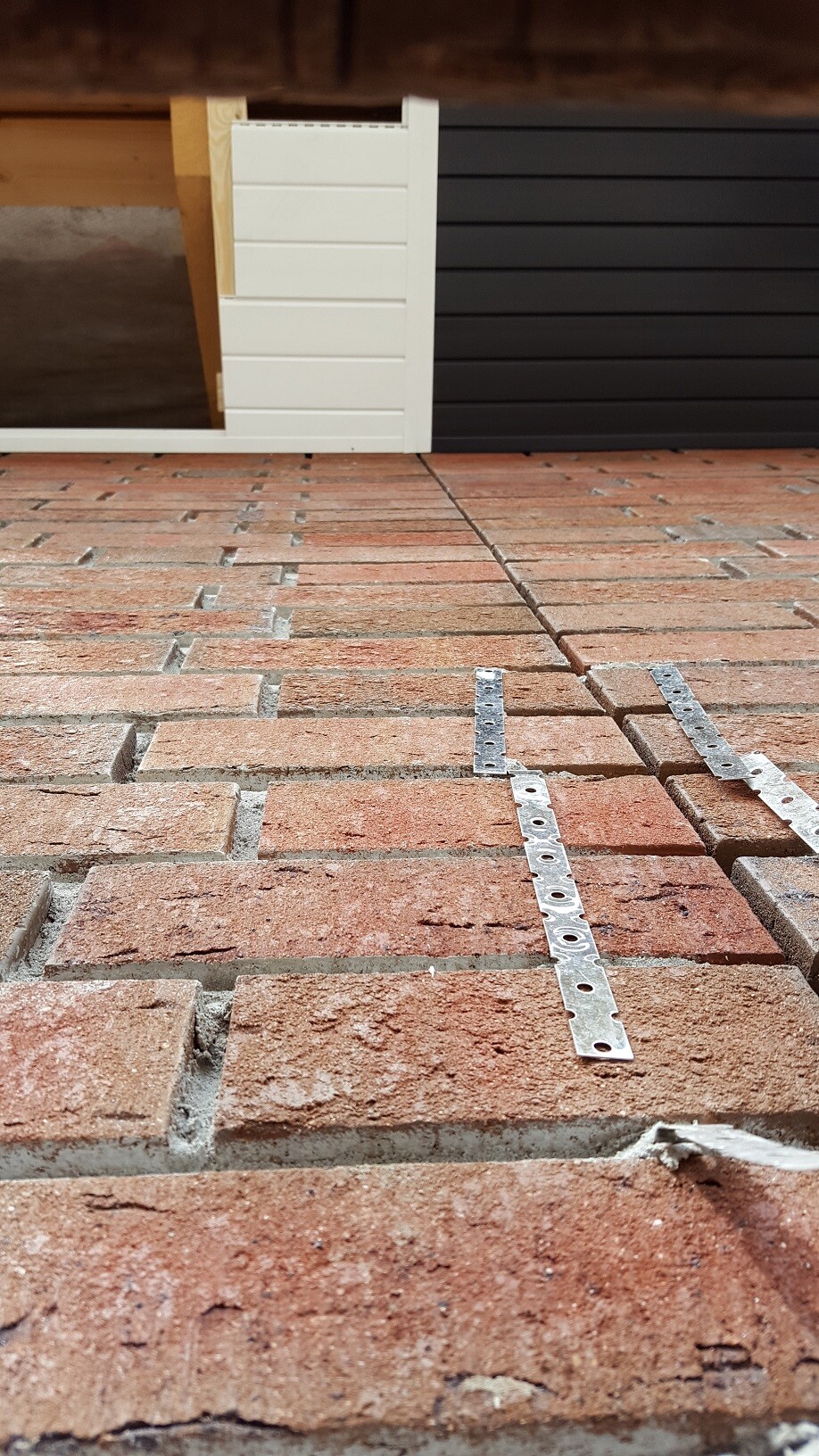Construction site with red brick floor, white wall panels, and metal mounting rails