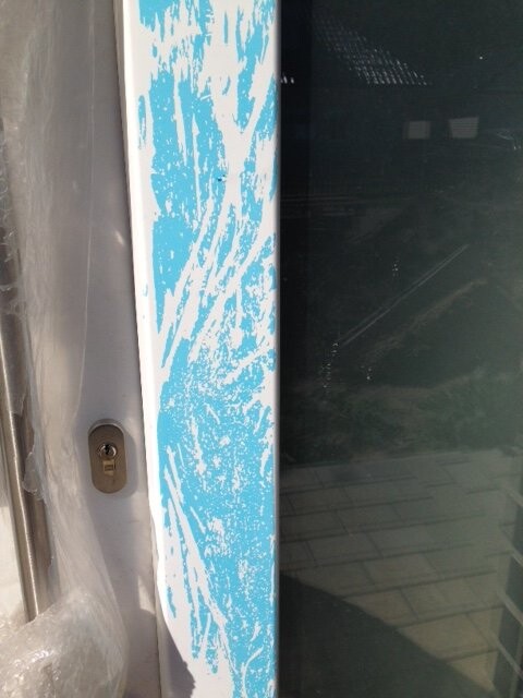 Door frame with blue protective film on the edge, construction site in the background