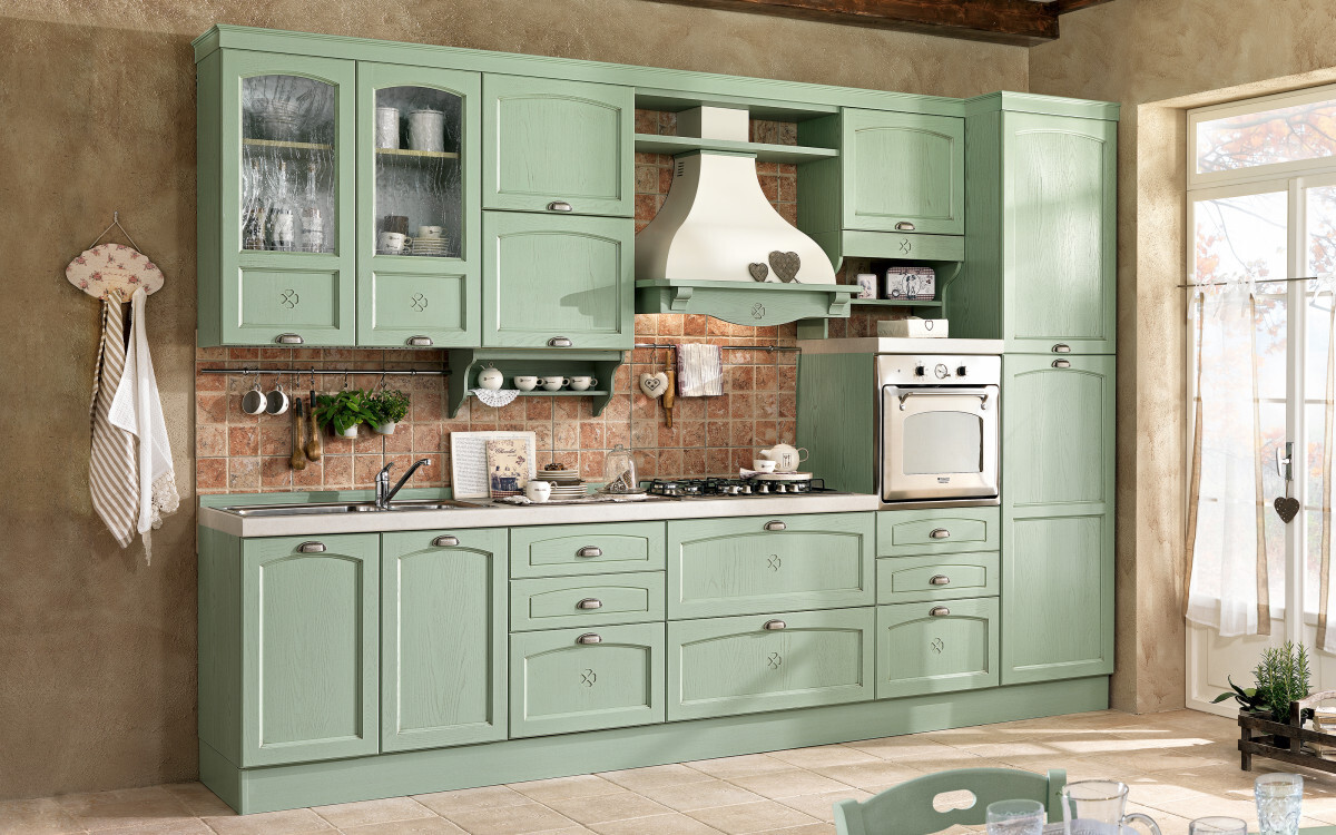Pastel green kitchen unit with oven, range hood, and tiled backsplash.