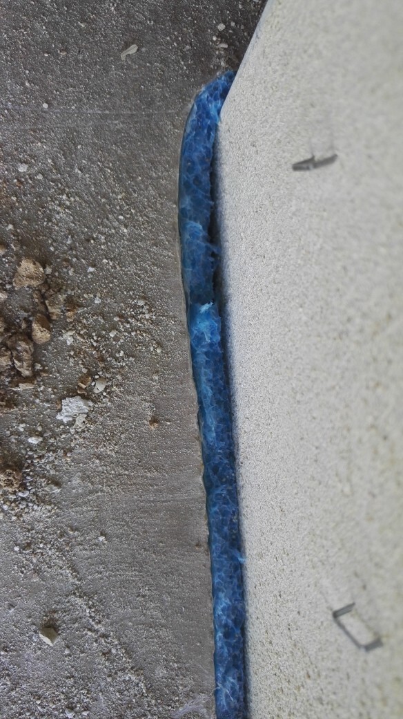 Blaue Wasserabdichtung an Fundamentwand im Rohbau, staubiger Boden