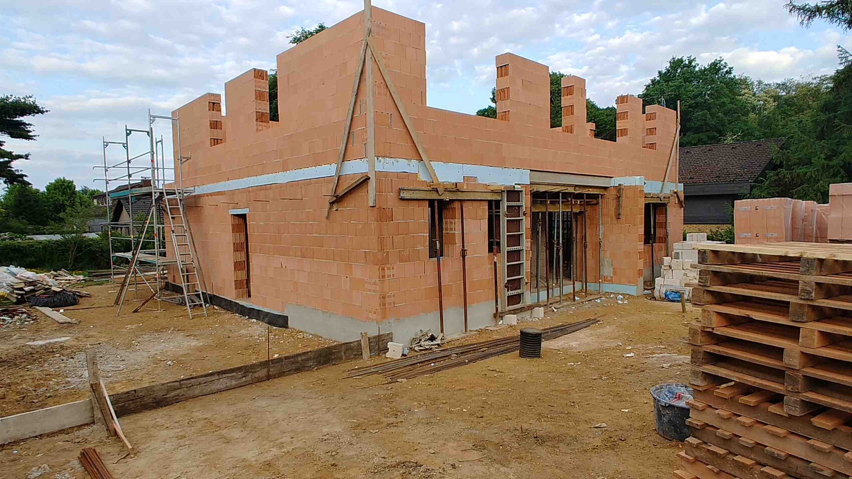 Partially completed brick building in shell construction, scaffolding and wood stacks on site