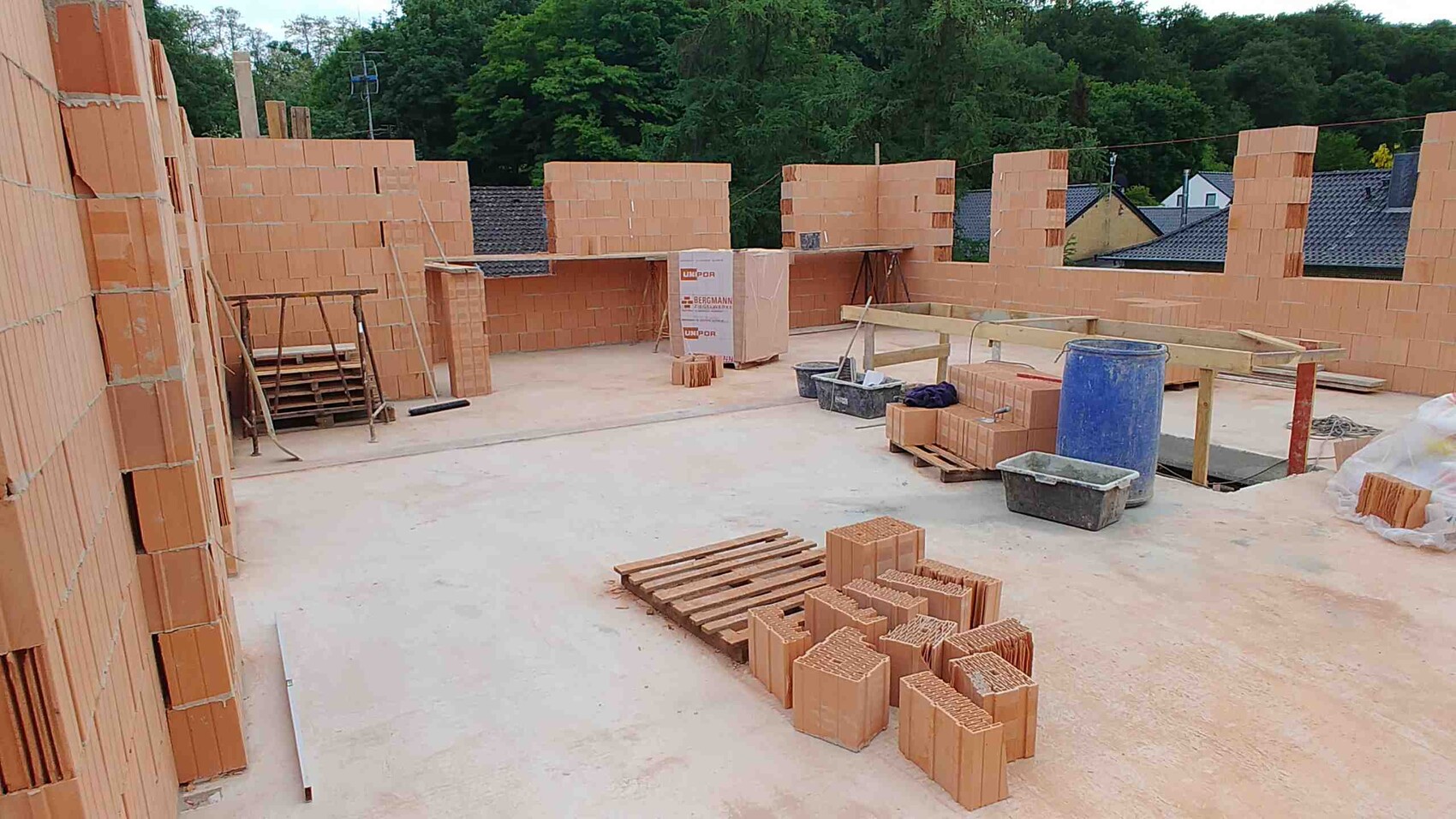 Construction site with open brick walls, stacked bricks and construction equipment.