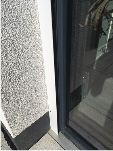 Close-up of a window frame next to a rough wall plaster texture.
