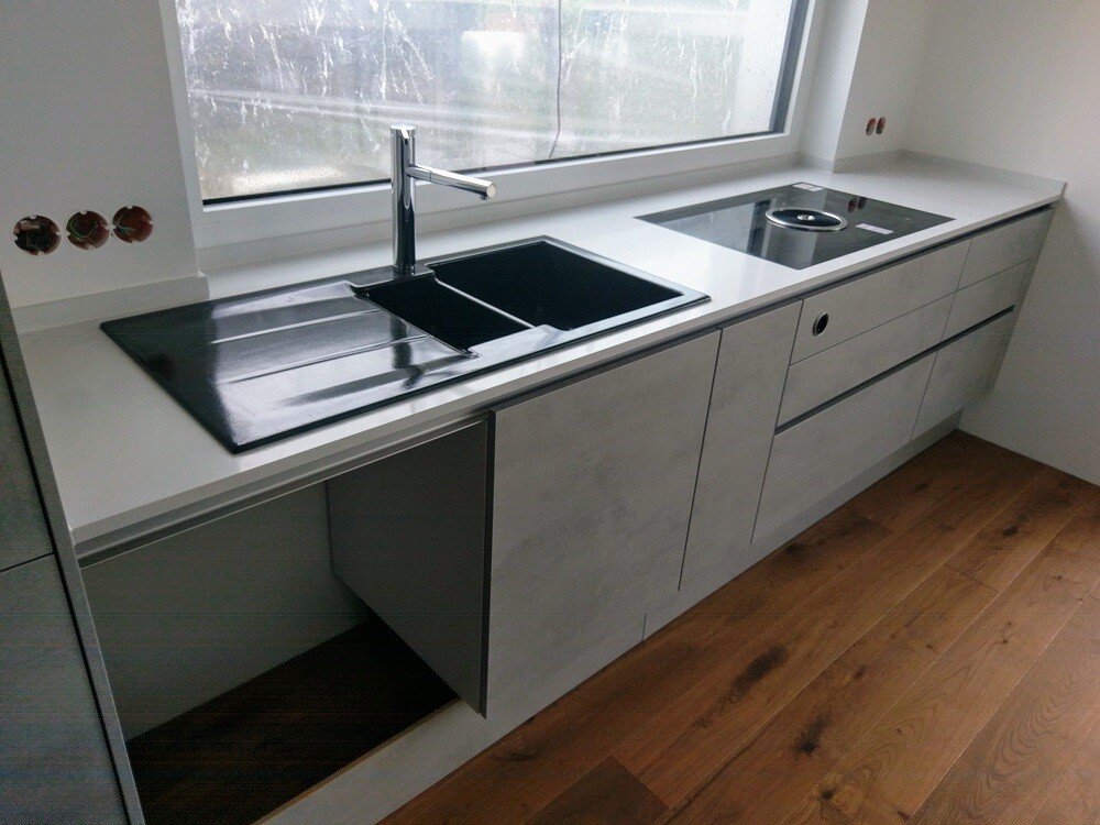 Modern kitchen unit with sink, dark countertop, and induction cooktop in front of window
