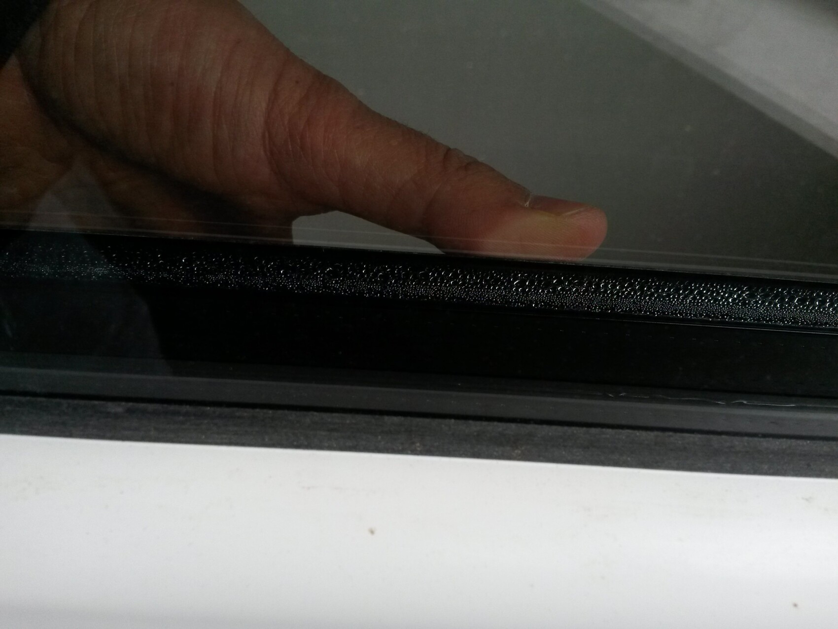 Close-up of a hand on a window seal at the window frame