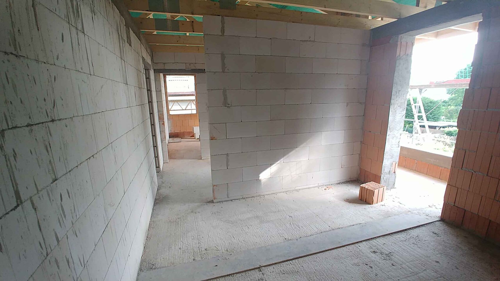 Shell interior with concrete block walls, wooden ceiling, open passage, and a block on the floor.