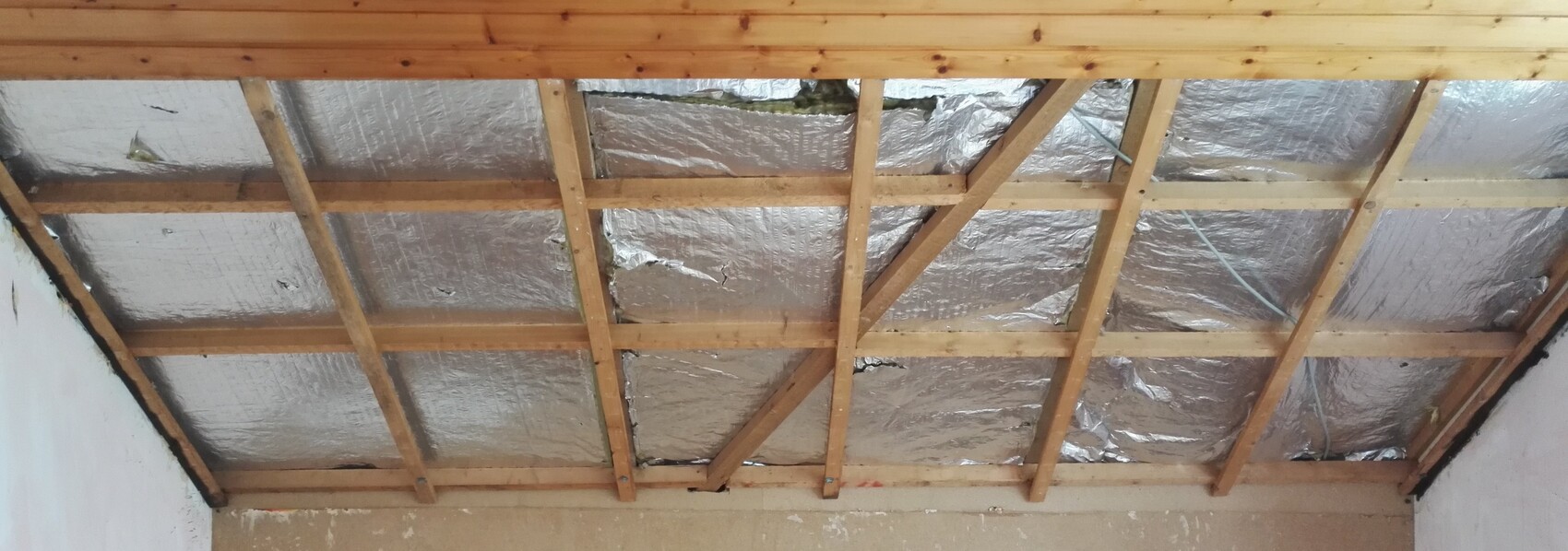 Attic with wooden beams and reflective insulation foil between rafters