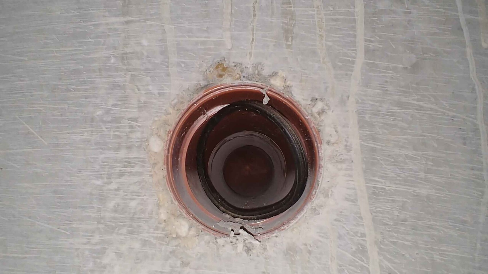 Runder Abfluss im Betonboden einer Baustelle mit rotem Ring im Sanitärbereich