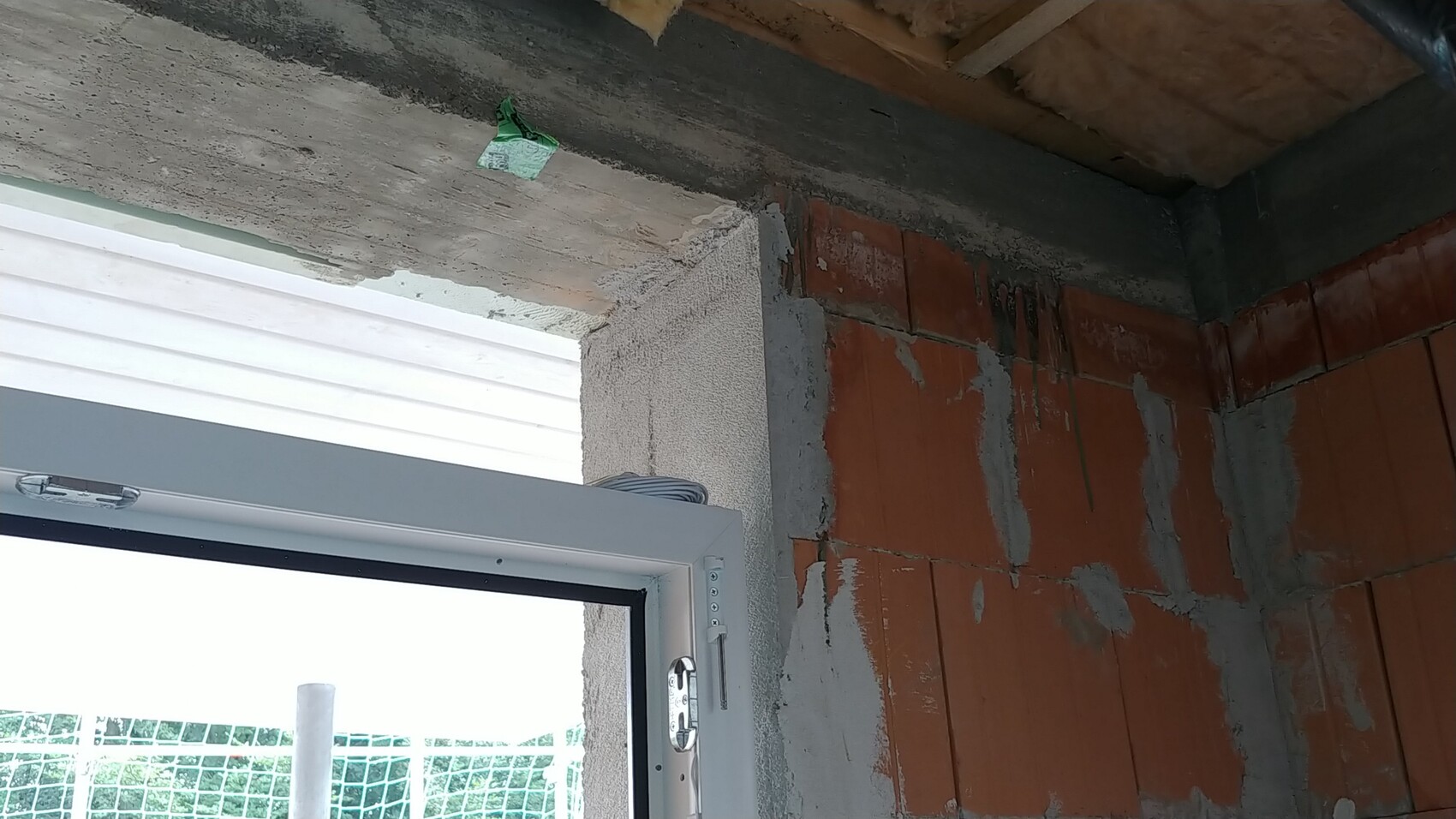 Unplastered interior brick wall next to window frame in shell construction