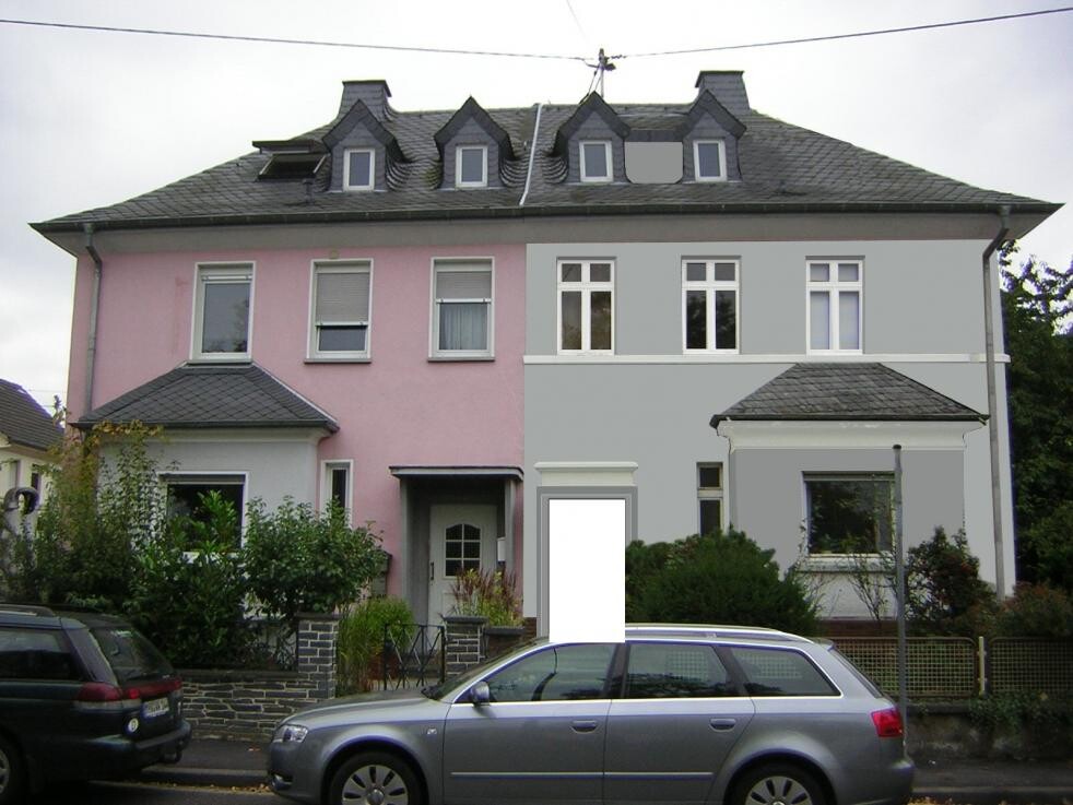 Zweifamilienhaus-Frontansicht mit pinker und grauer Fassade und Parkplätzen vor dem Haus.