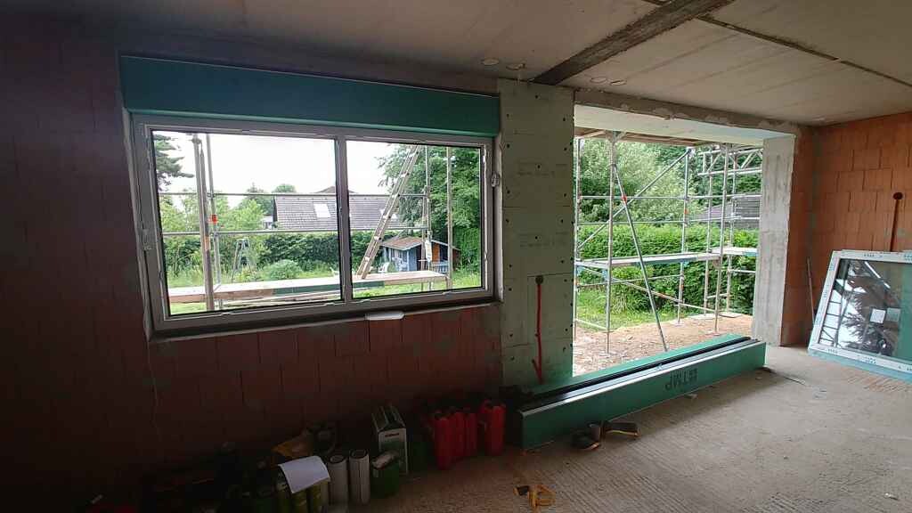 Unfinished interior of a house with large window and scaffolding outside