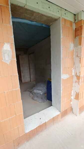 Construction site: open doorway to an empty interior space with brick walls; blue container.