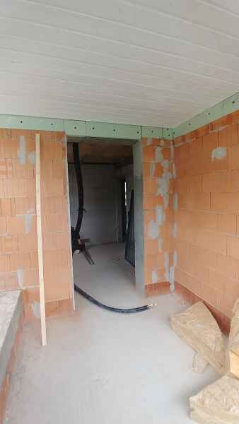 Passage through unplastered brick walls, cables on the floor and construction timber on the right.