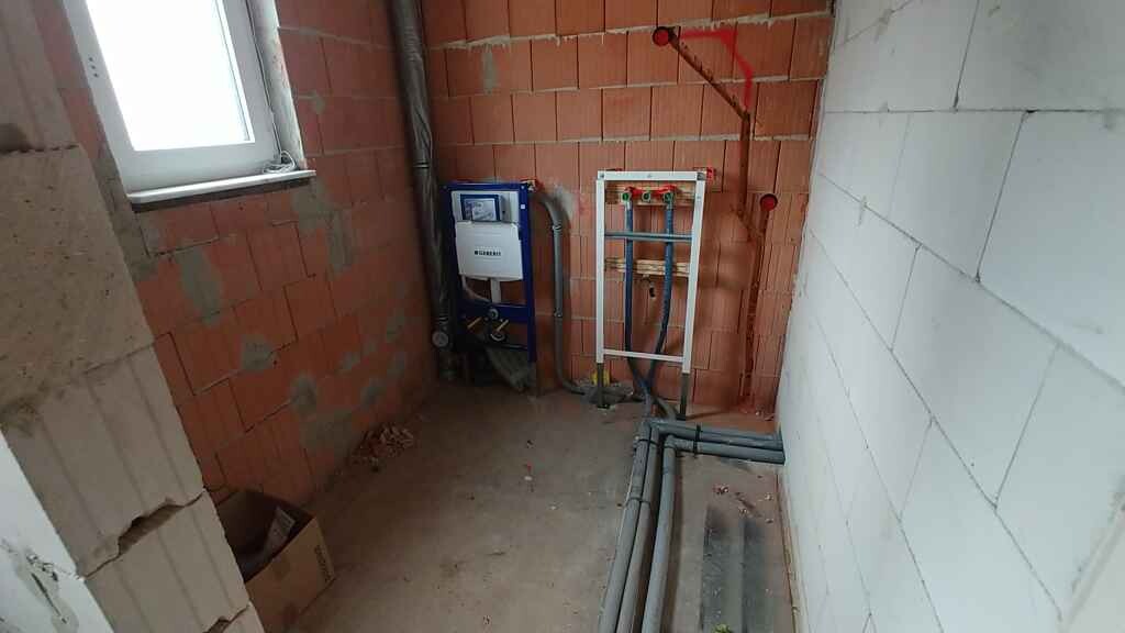 Shell bathroom with toilet installation frame, sanitary pipes and brick walls