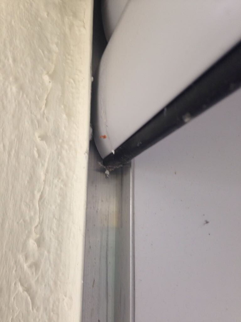 Close-up of a door frame with a black cable on the wall, dust and damage visible.