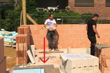 Two construction workers working on the shell; masonry blocks, concrete blocks, and construction site visible.