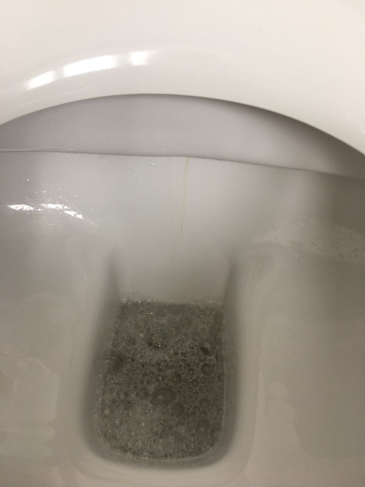 White toilet with foamy water in the bowl