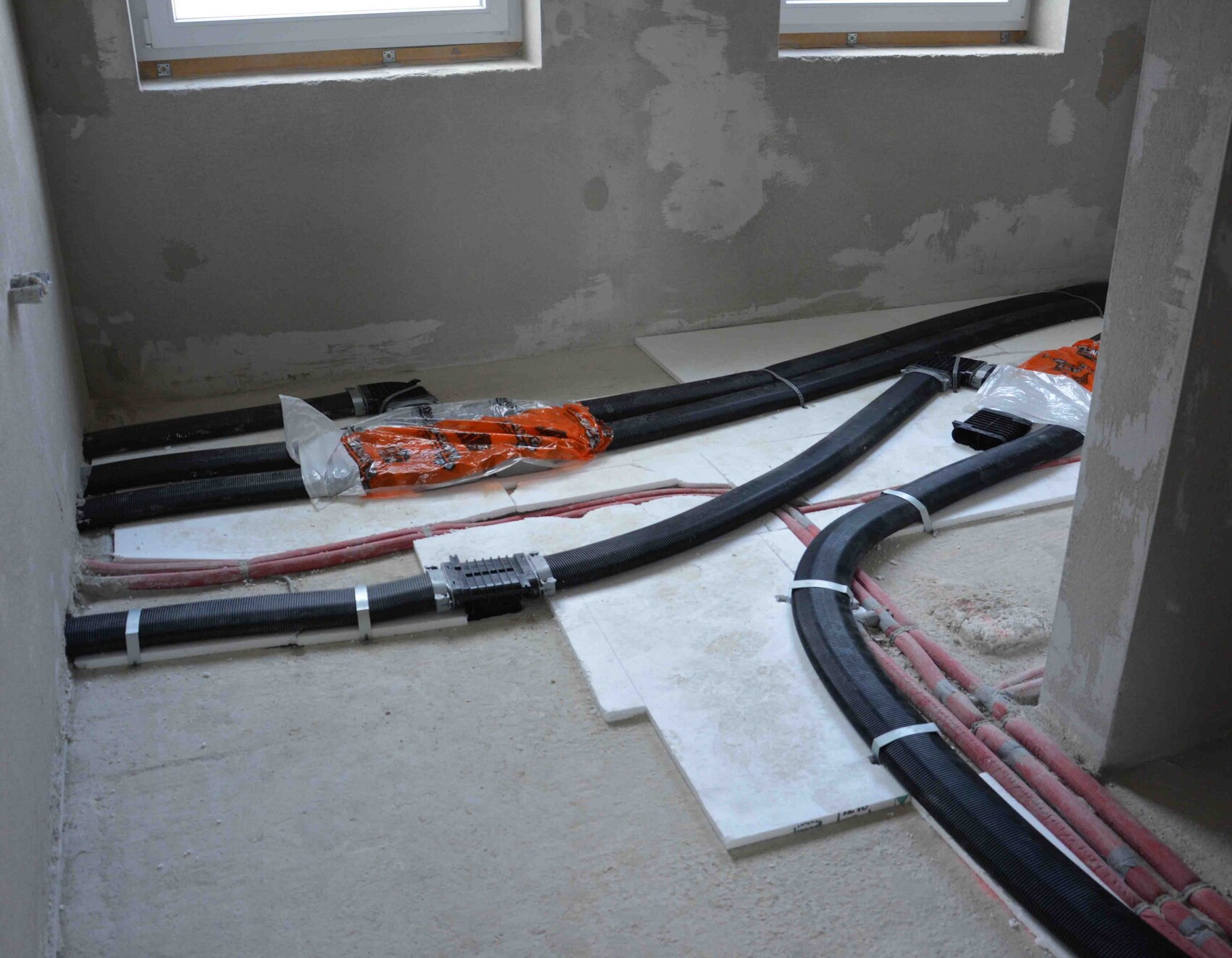 Construction room with black conduit pipes and red pipes on the floor