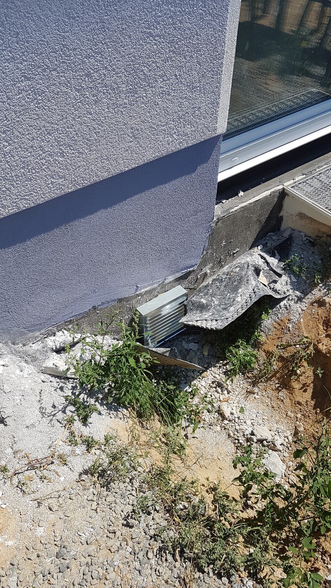 Außenwand mit rohem Fundament, Schutt und Unkraut am Baugrund