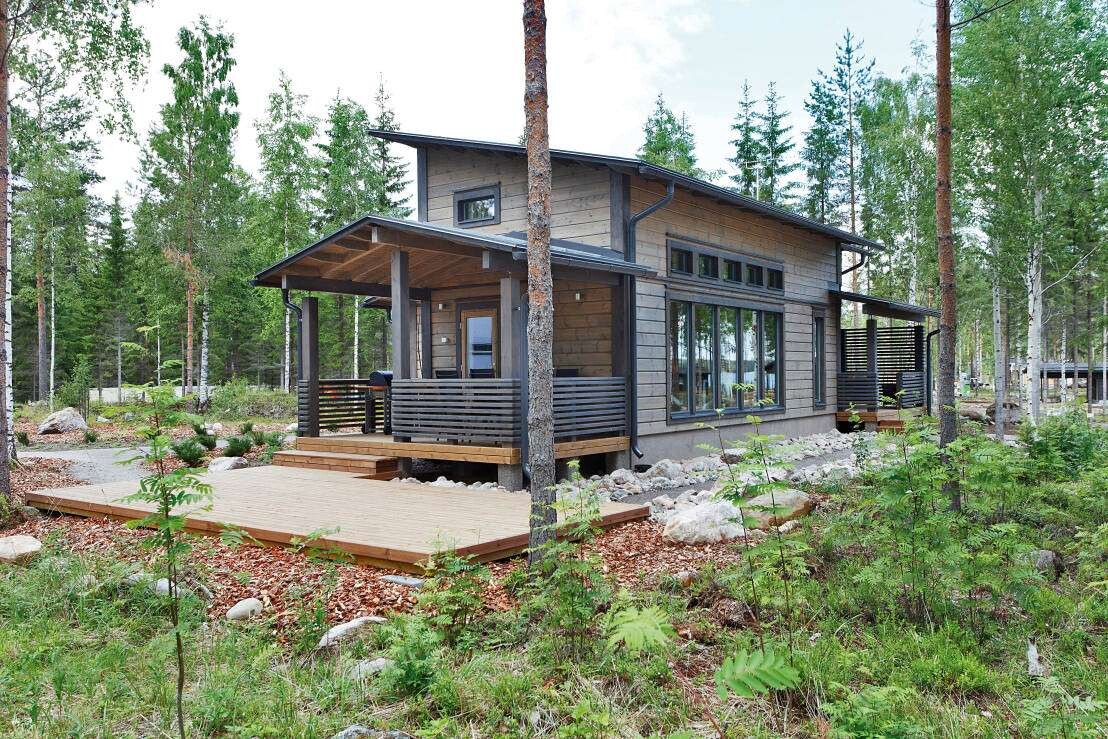 Modernes Holzhaus im Wald mit Veranda und großen Fenstern