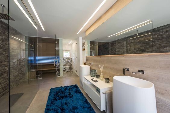 Modernes Badezimmer mit Glasdusche, rundem Waschbecken, Holzverkleidung und LED-Beleuchtung