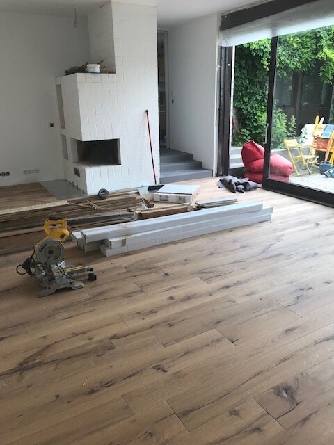 Wohnzimmer im Umbau: Holzboden, Bauholzstapel, Kappsäge, Glastür zur Terrasse.