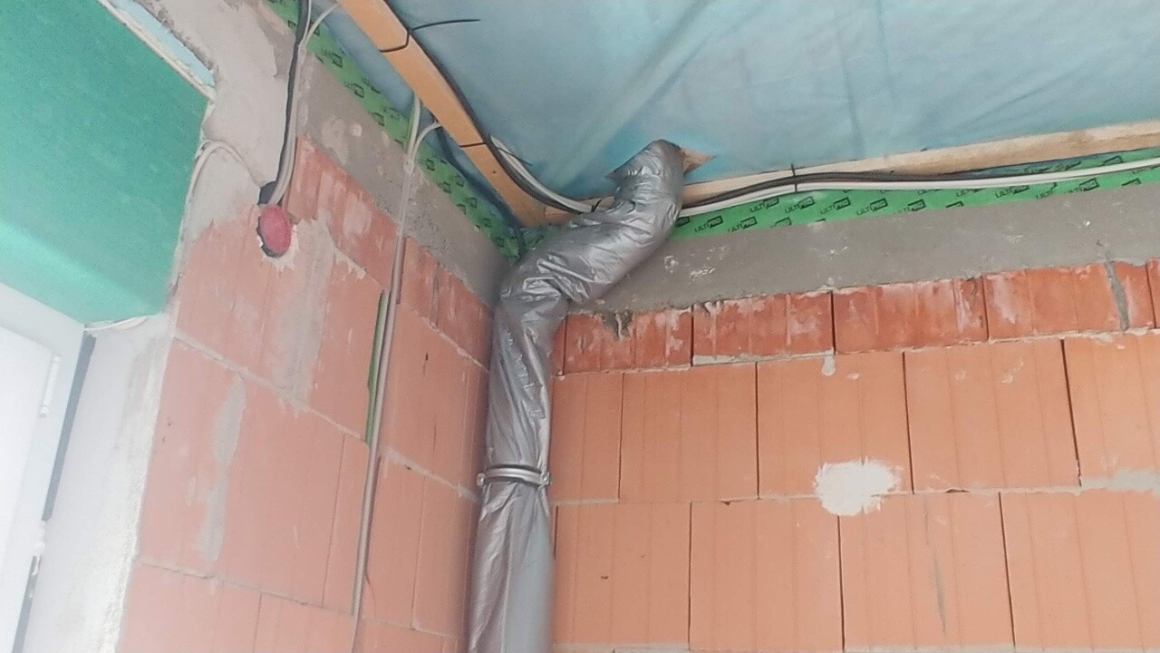 Unplastered interior with exposed brick walls, insulation, and installation pipes.