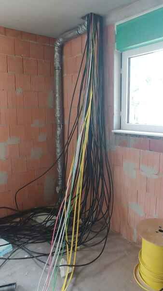 Construction site: Loose electrical cables hanging on red brick wall next to a window.