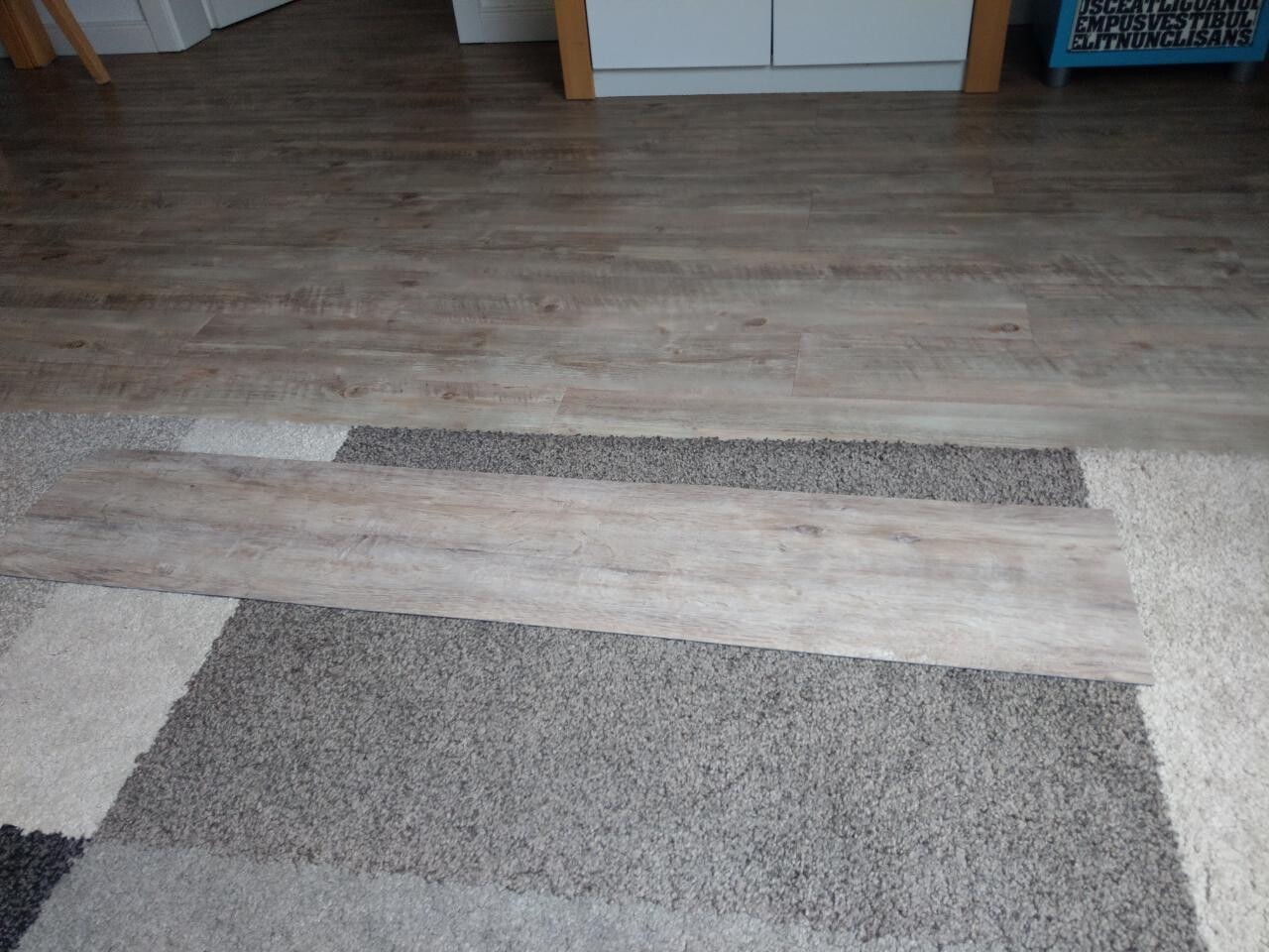 Laminate floor planks lying on carpet, sample pieces indoors.