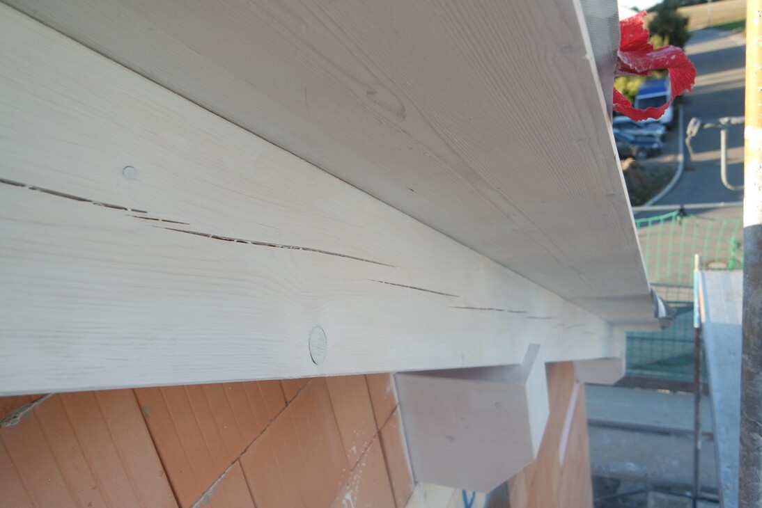 White-painted wooden beams on a construction site facade, view from below the building.