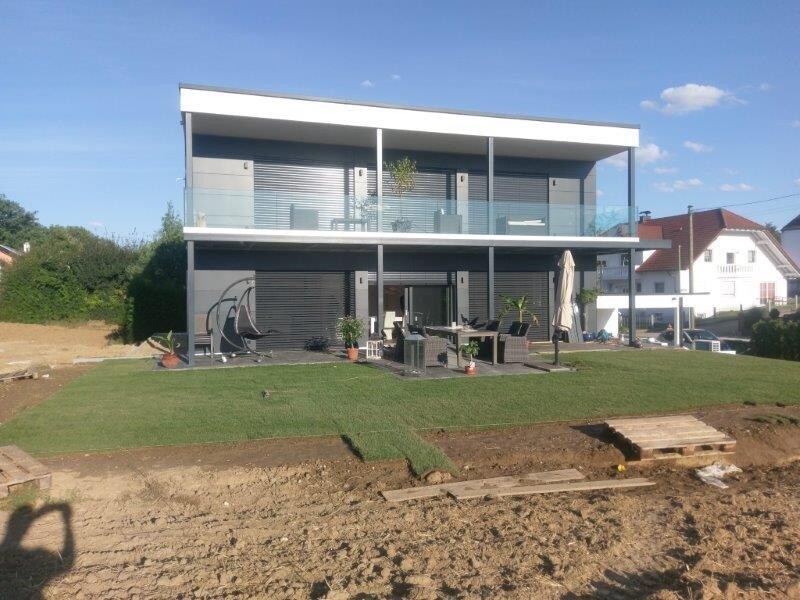 Moderne zweigeschossige Villa mit Glasbalustrade, Sitzecke und Terrasse.