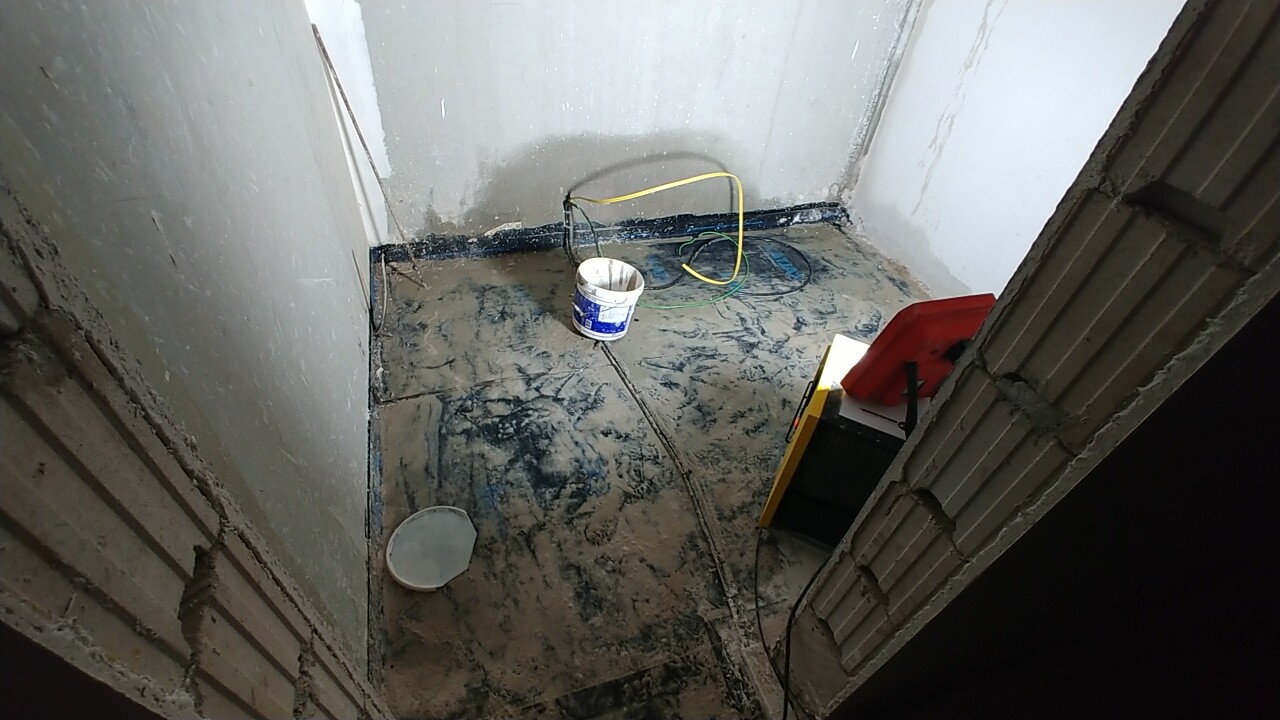 Rohbau-Kellerraum mit unfertigem Boden, Kabel, Eimer und Werkzeug