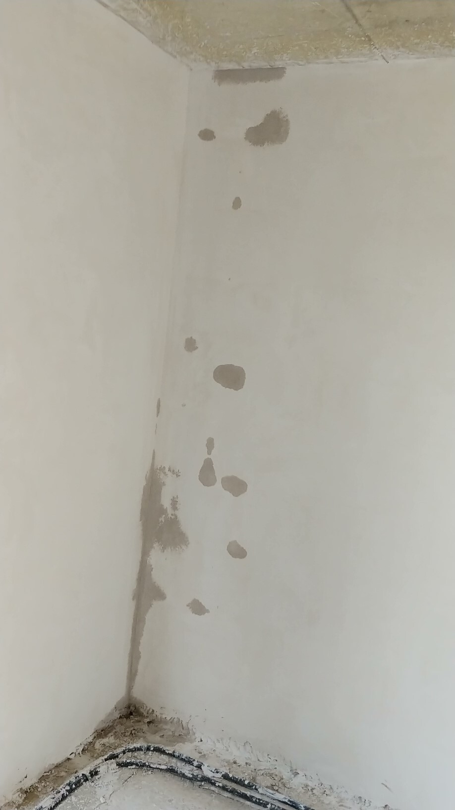 Innenwand-Ecke mit Feuchtigkeitsspuren und Putzschäden am Boden