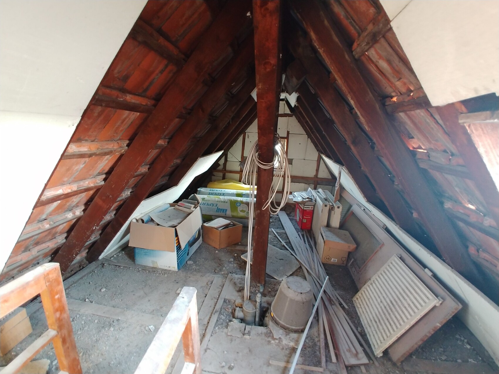 Dachgeschoss-Raum im Umbau mit Holzbalken, Baustoffen und Kabeln